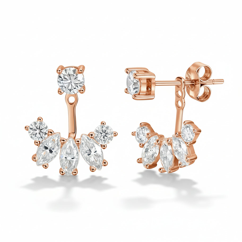 Rose gold earrings with clear gemstones on a light green fabric background