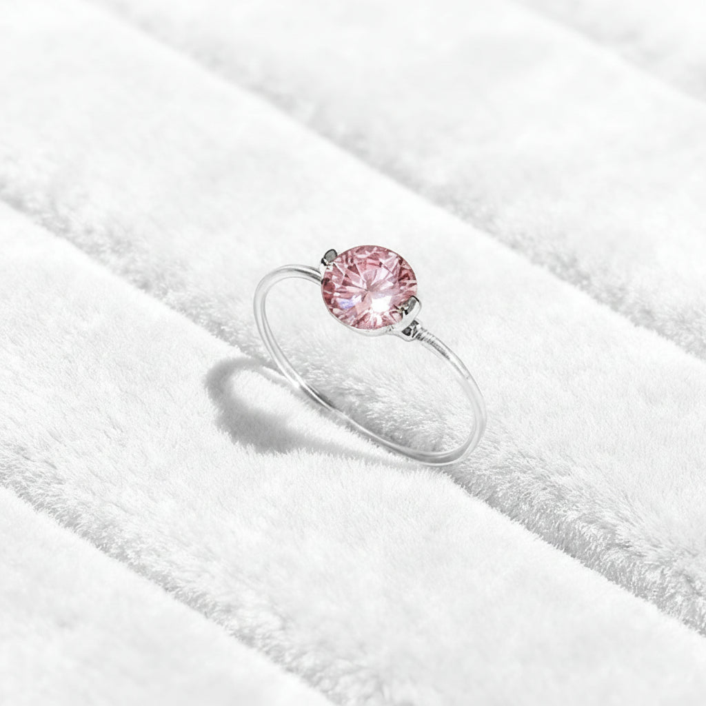 Ring with a pink gemstone on a green textured fabric background