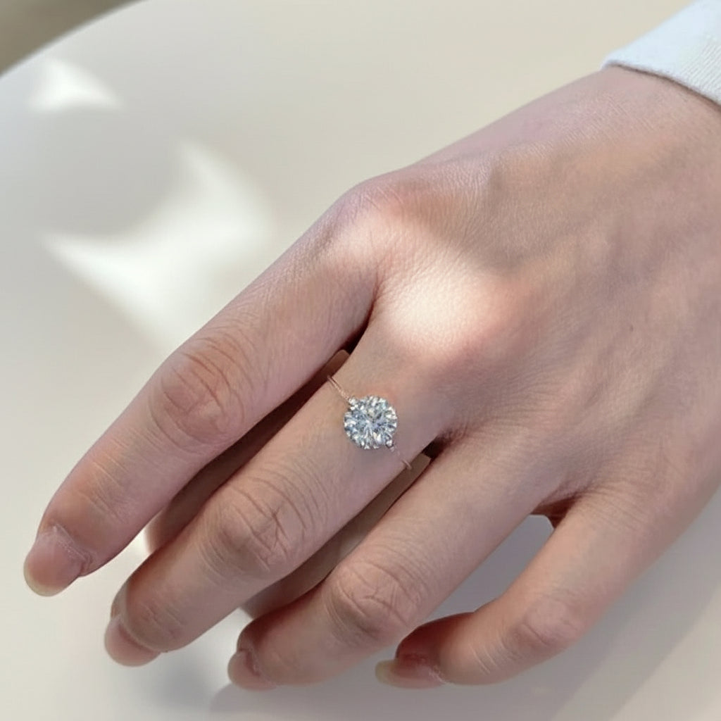 Hand wearing a diamond ring holding a white cup.