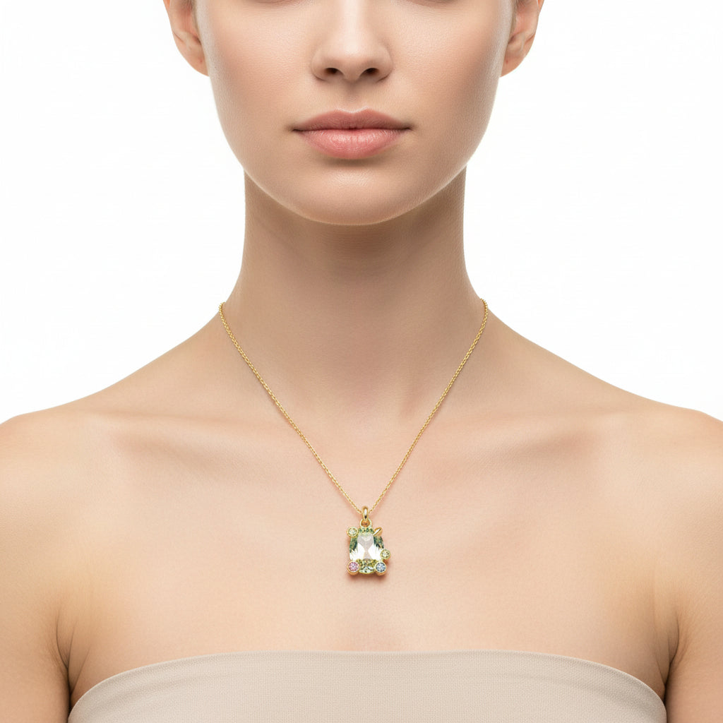 Gold necklace with a green gemstone pendant on a white background