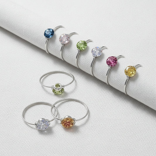 Set of silver rings with multicolored gemstones on a white fabric background