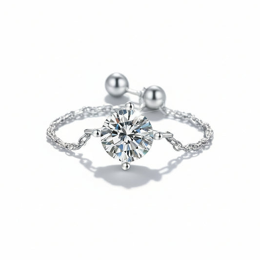 Silver ring with a large diamond and smaller pearls on a green fabric background