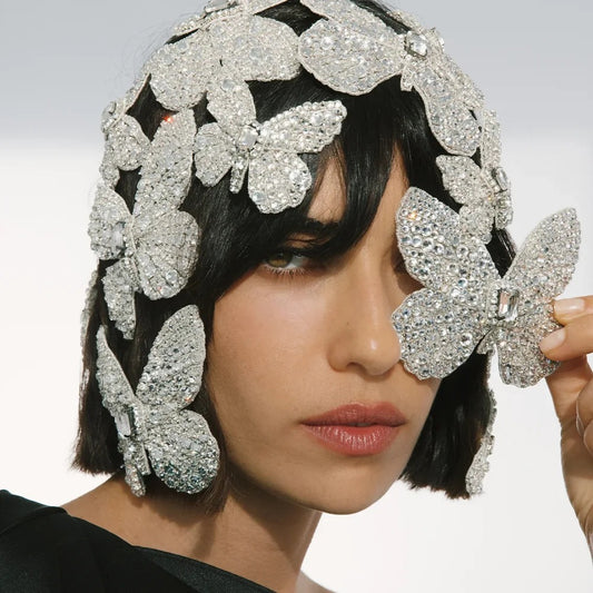 Silver butterfly headpiece worn by a model with a neutral background