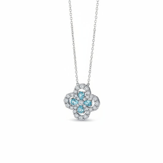 Silver necklace with a floral pendant featuring blue stones on a brown surface.