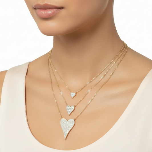Three heart-shaped diamond pendants on gold chains against a white background
